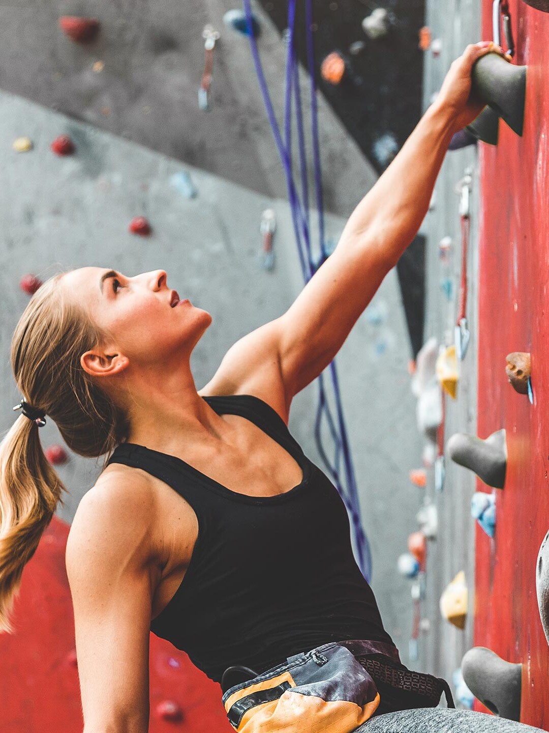 Eine Frau an einer Kletterwand mit dem Fokus auf den nächsten Zug