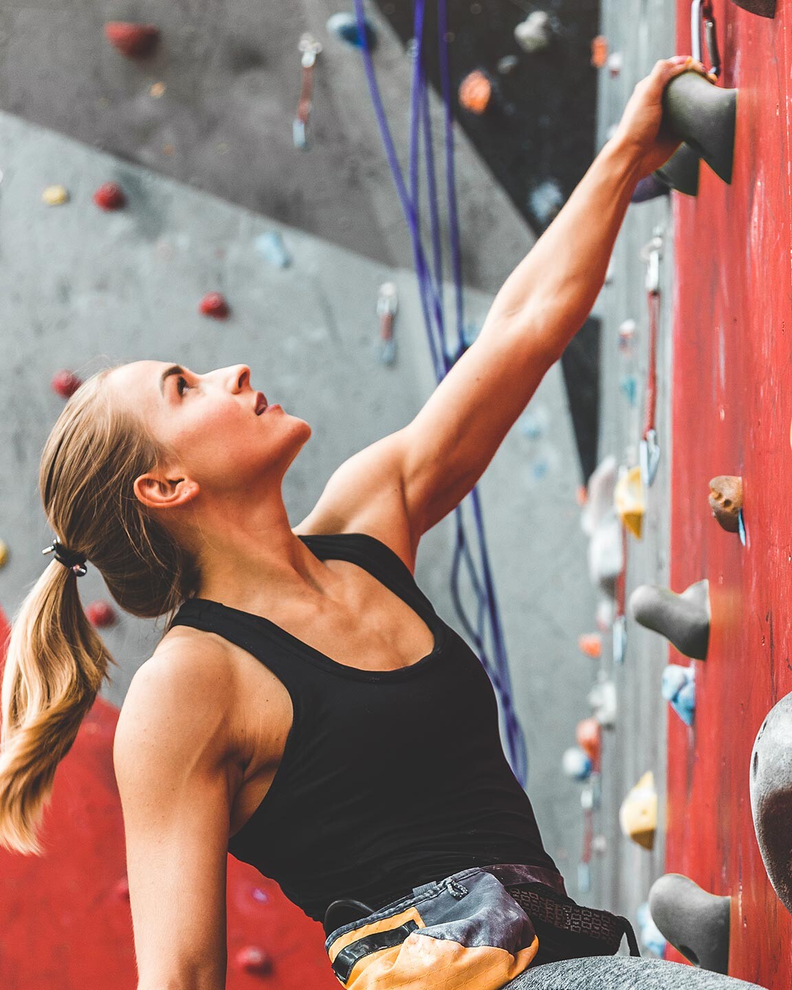 Eine Frau an einer Kletterwand mit dem Fokus auf den nächsten Zug