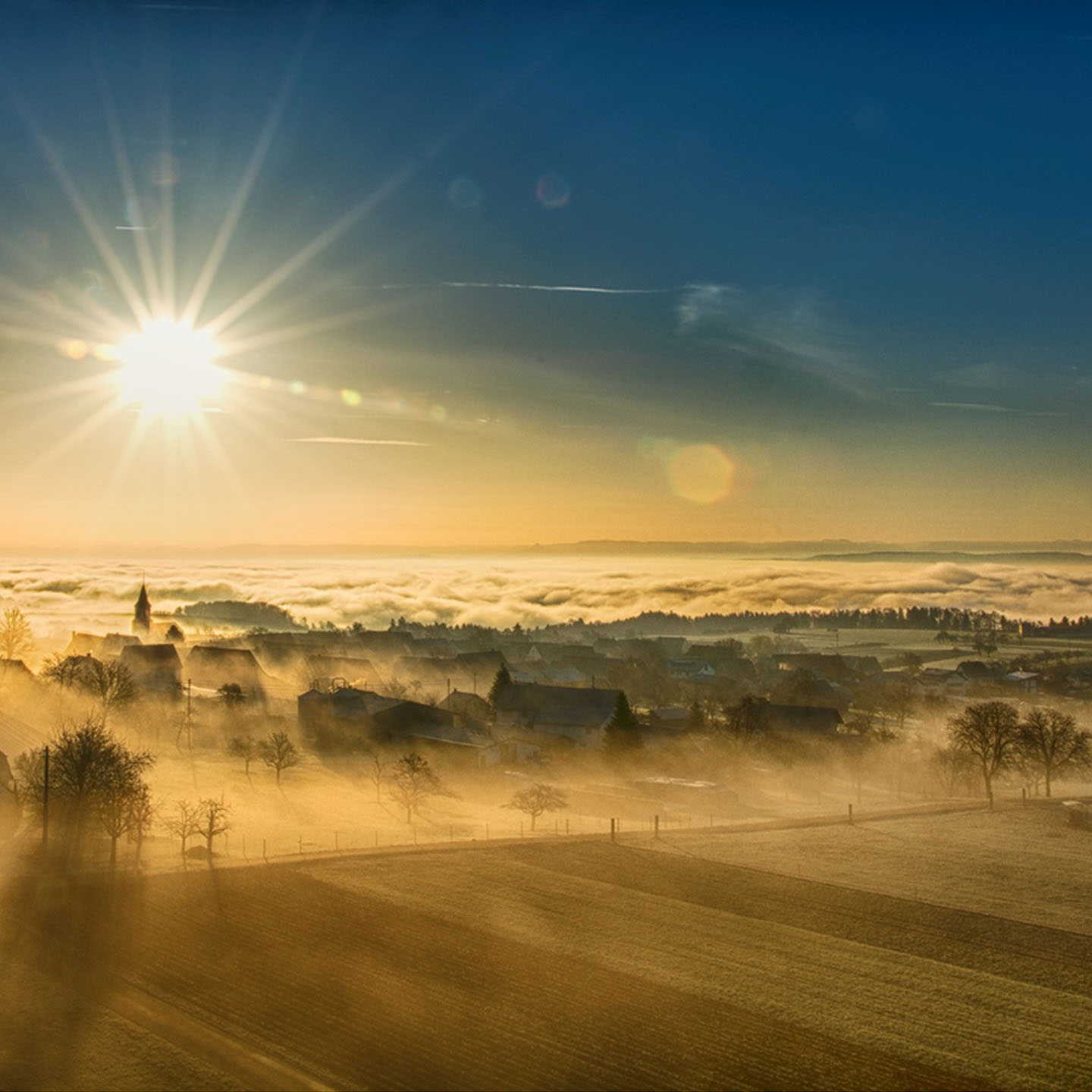 Die Sonne geht im Winter über einem Nebelbedeckten Dorf auf